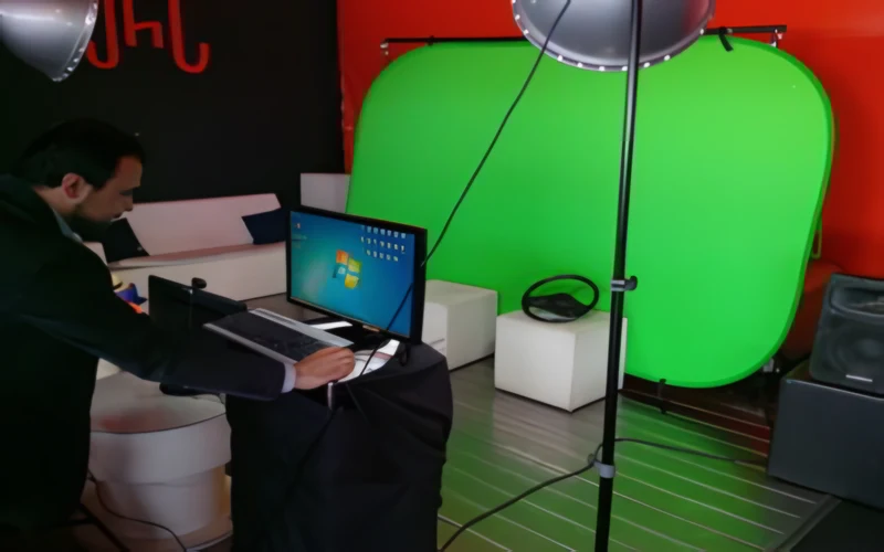 Montaje de un photocall con croma verde, foco con paraguas y técnico con portátil