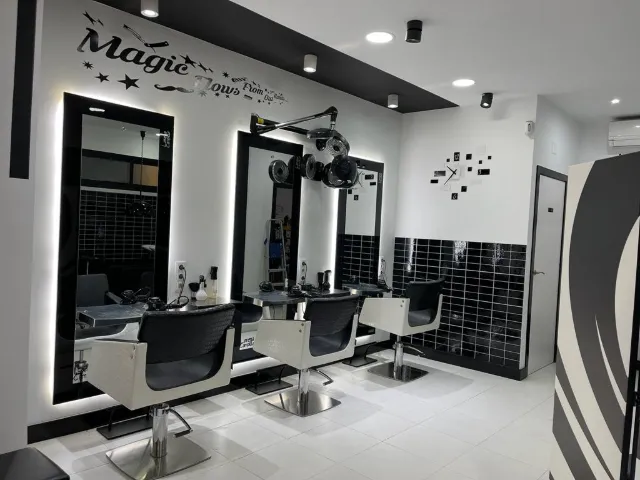 La pared de espejos del salón, con marcos negros iluminados y sillones blancos