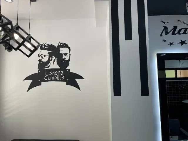 Pared del salón con el logotipo de Lorena Campillo sobre una ilustración de dos barberos
