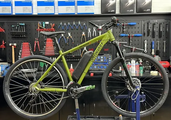 Bicicleta de montaña verde en el soporte del taller con un kit eléctrico Ciclotek recién montado