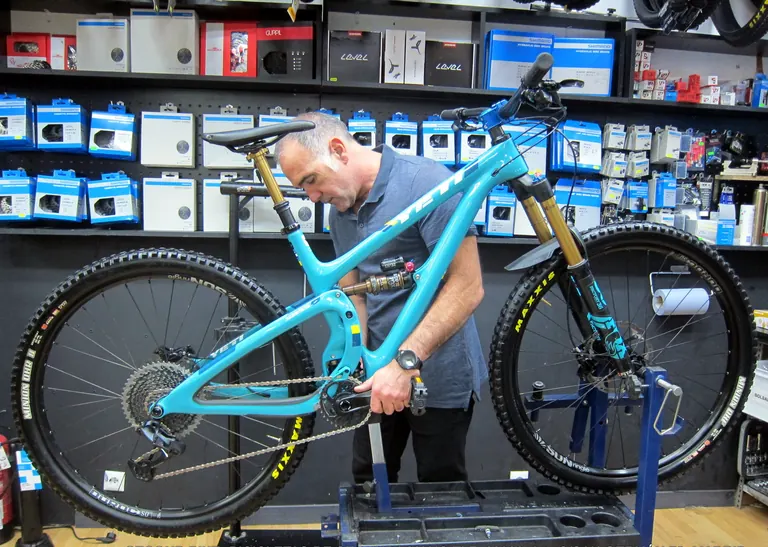 Mecánico de Secondbike ajustando una bicicleta de montaña de doble suspensión en el soporte del taller