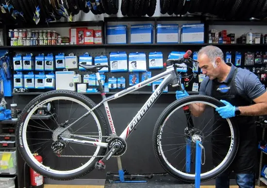 Mecánico de Secondbike revisando una bicicleta de montaña blanca en el soporte