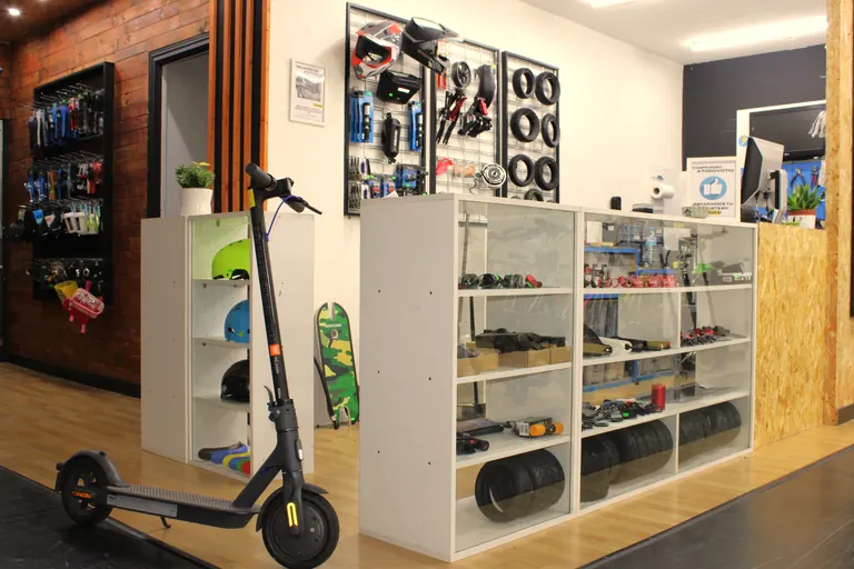 Rincón de A Todo Voltio dentro de la tienda, con un patinete eléctrico y estanterías de recambios